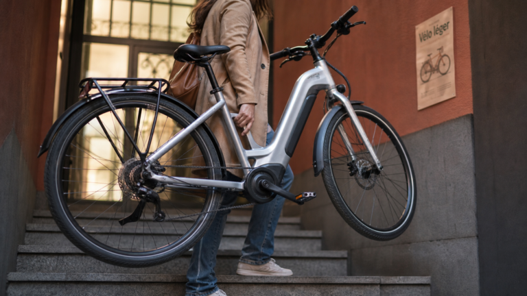 Moins de 15 kg, cadre bas et moteur compact : le vrai cahier des charges d’un vélo électrique femme léger Vélo électrique femme léger dans une entrée urbaine, cadre bas